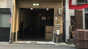 Un edificio con un amplio portón de garaje, una entrada visible y una escalera que lleva a un nivel superior.