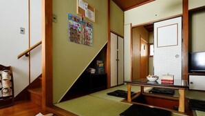 Una habitación japonesa tradicional con suelo de tatami, una mesa baja con un tazón, un televisor y una puerta corredera.