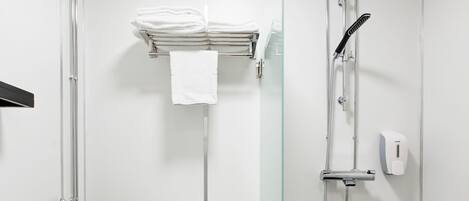 A modern bathroom with a white toilet, a glass shower enclosure, and a black-tiled floor.