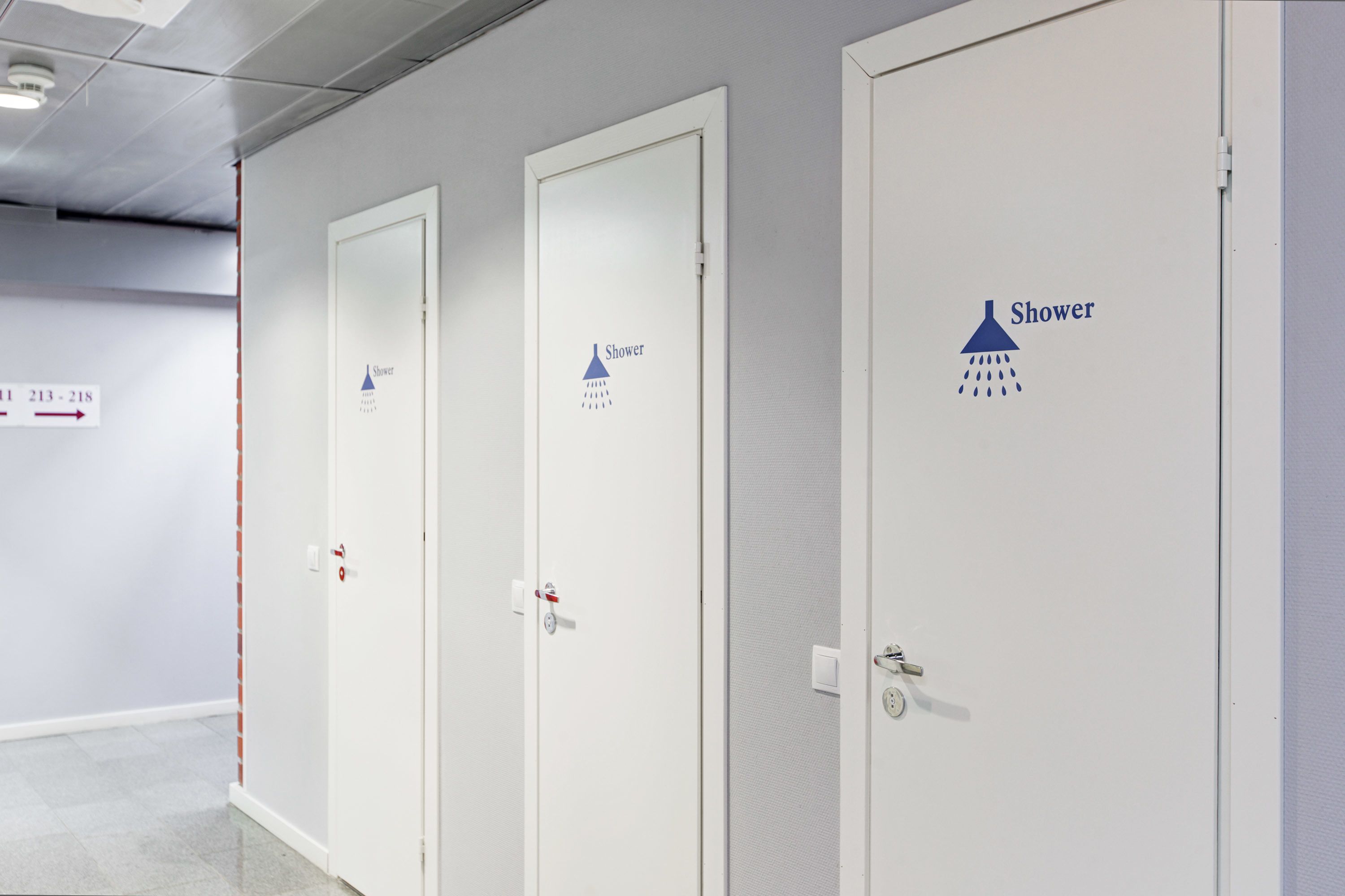 Three white doors with shower symbols and the word "Shower" on them, indicating a shower facility.