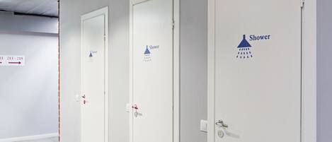 Tres puertas blancas con símbolos de ducha y la palabra 'Shower' escrita en ellas, indicando un cuarto de baño con ducha.