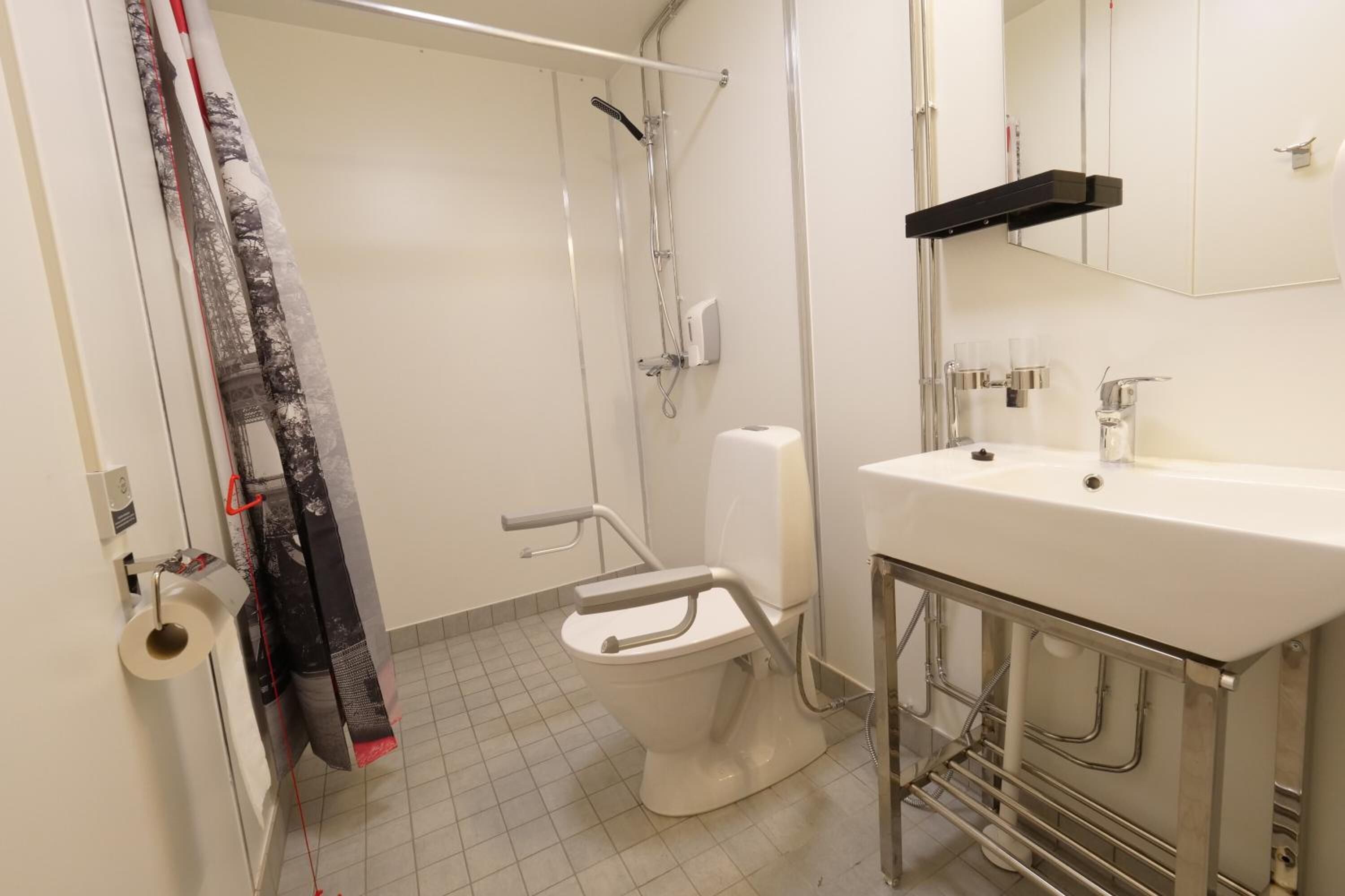 Un baño con inodoro, ducha, lavamanos y toallero.