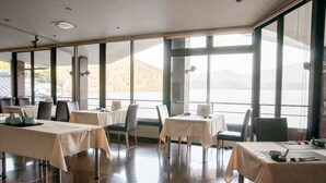 Un restaurante con mesas dispuestas para comer, amplias ventanas que ofrecen vistas al exterior y un interior moderno y cuidado.