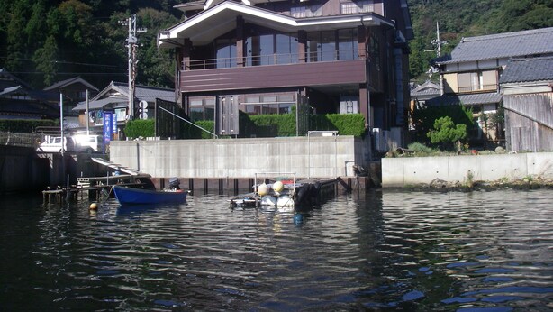 Una casa moderna de dos pisos con balcón, cerca de una masa de agua.