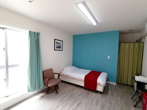 Una habitación con cama, una silla, un escritorio y una ventana con cortinas.