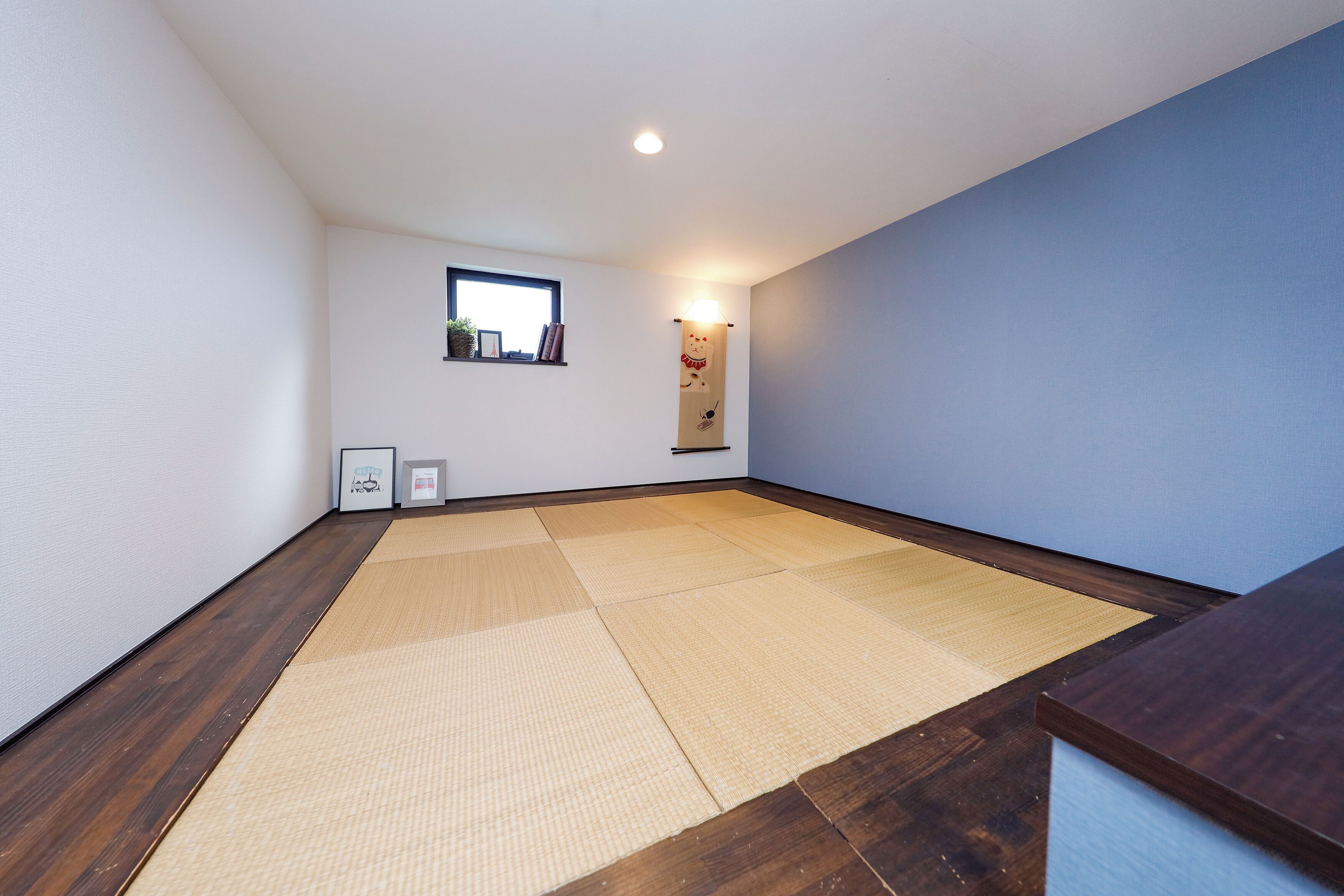 A room with tatami mats, a small window, and a wall-mounted light fixture.
