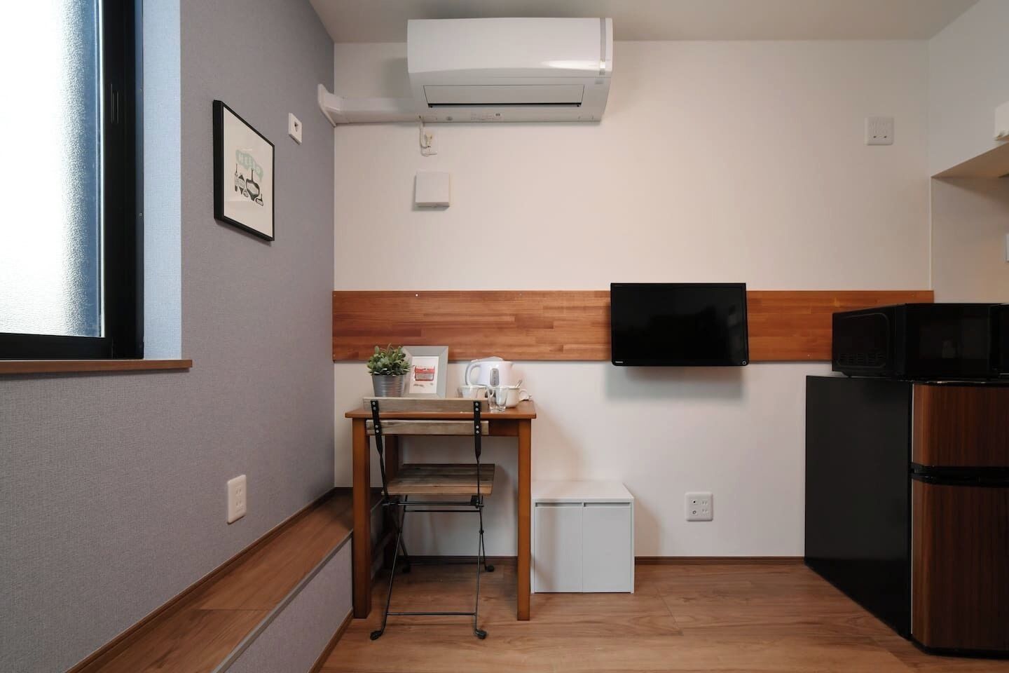 Una cocina compacta con microondas integrado, un refrigerador pequeño y una encimera de madera con lavamanos.