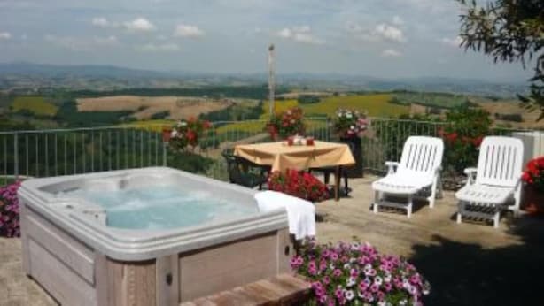 A hot tub with a table and chairs on a balcony with a scenic view. - Canalicchio: Apartment within farmhouse and terrace with Jacuzzi for 4 persons (Canalicchio)
