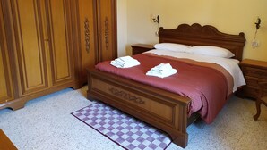A bedroom with a wooden bed, a checkered rug, and a wardrobe. - Canalicchio: Apartment within farmhouse and terrace with Jacuzzi for 4 persons (Canalicchio)