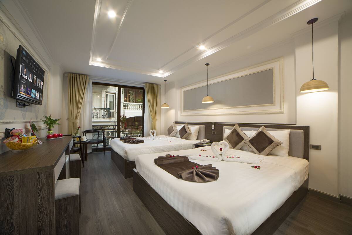 Une chambre d’hôtel avec deux lits, un bureau et une télévision.