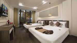 A hotel room with two beds, a desk, a TV, and a large window with curtains. - Galliot Central Hotel (Hanoi)