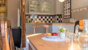 Una mesa de madera con un frutero, un florero y vasos transparentes.
