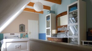 Un dormitorio con techo inclinado, cama, cómoda, espejo y armario.