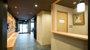 A hallway with a reception desk, a framed picture on the wall, and a tiled floor. - Shiki Suites - Kyoto Umekoji (Kyoto)