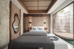 A modern hotel room with a large bed, a small seating area, and a view of the outdoors. - La Vie Villa Seminyak by Ini Vie Hospitality (Legian)