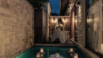Zona de piscina con mesa lista para comer, velas y un centro de mesa decorativo.