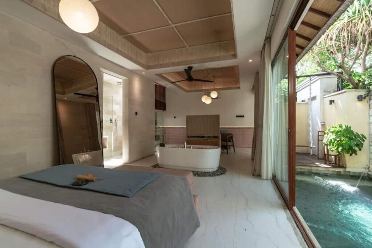 A bedroom with a bed, a bathroom, a kitchen, and a pool.