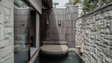 A spa area with a circular hot tub, stone walls, and a glass partition.