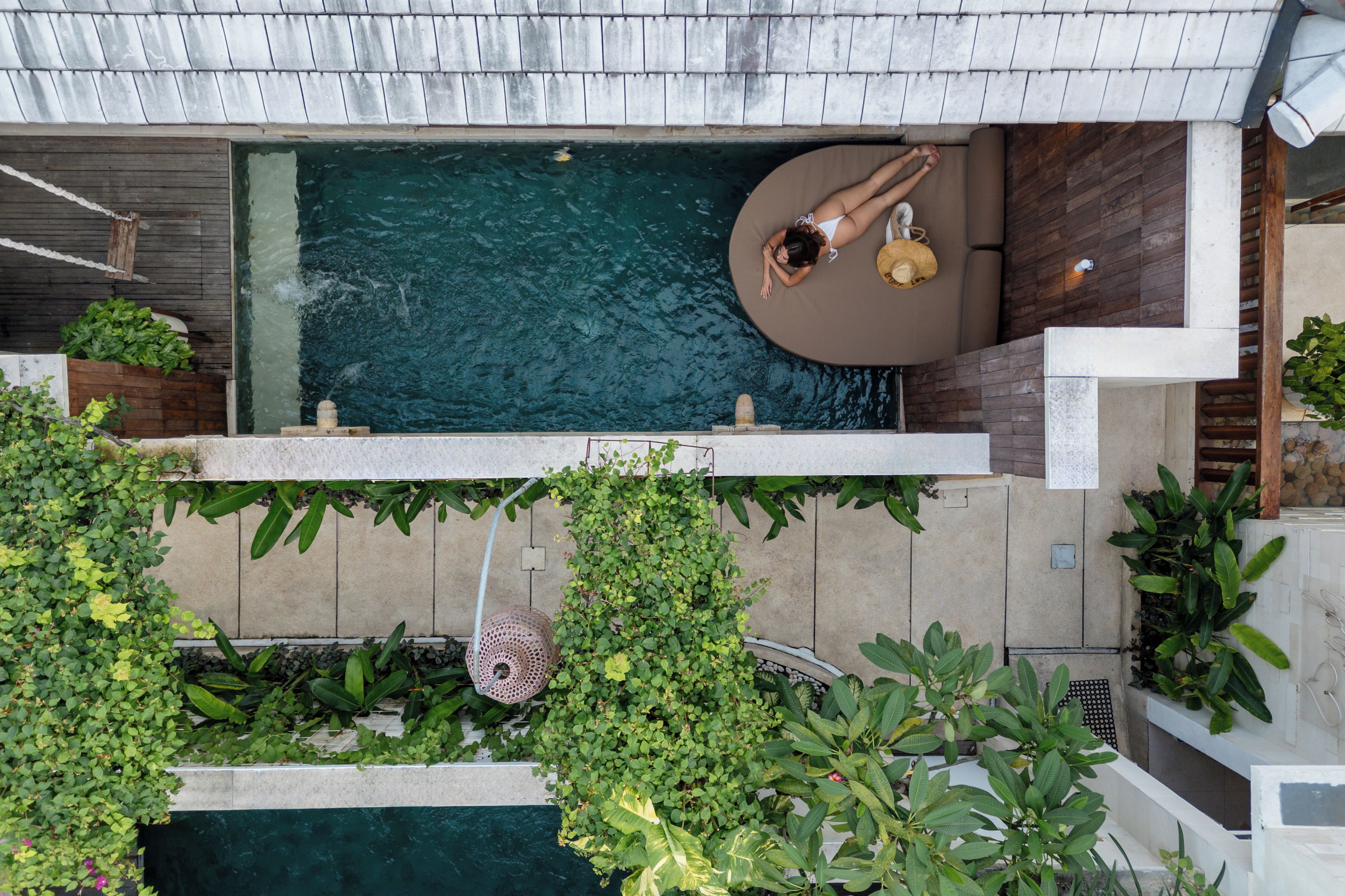 Una piscina al terrat amb una zona d'estar circular i vegetació abundant al voltant.