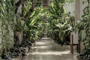 A corridor lined with lush green plants and a hanging light fixture. - La Vie Villa Seminyak by Ini Vie Hospitality (Legian)