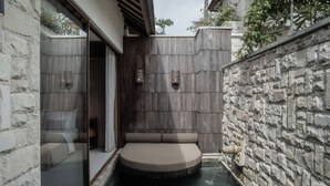 A spa area with a circular hot tub, stone walls, and a glass partition. - La Vie Villa Seminyak by Ini Vie Hospitality (Legian)