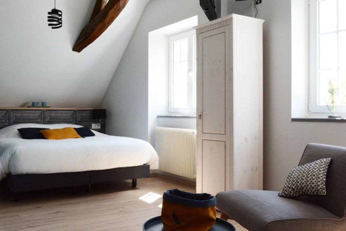 Een slaapkamer met een bed, een stoel, een kledingkast en een raam.