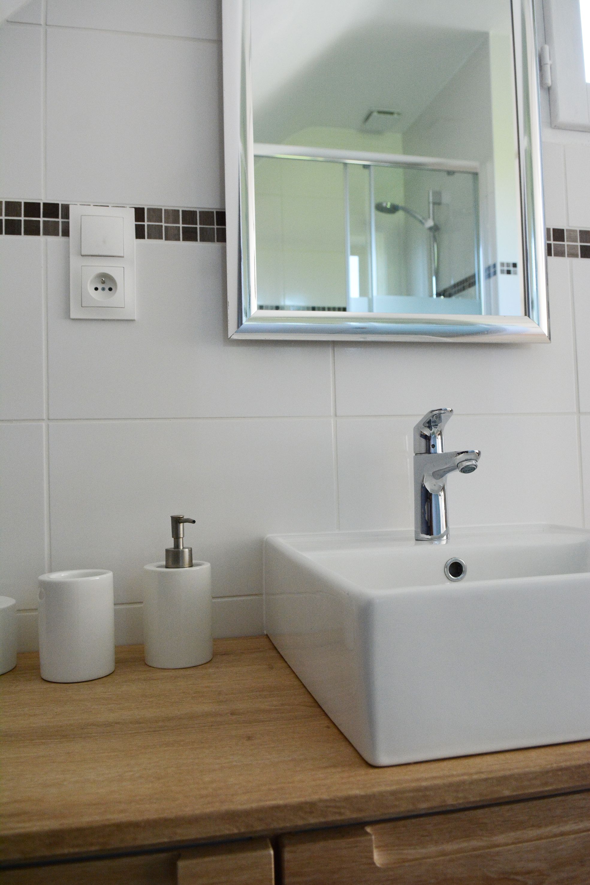 A bathroom with a white sink, a mirror, and a toilet paper holder.