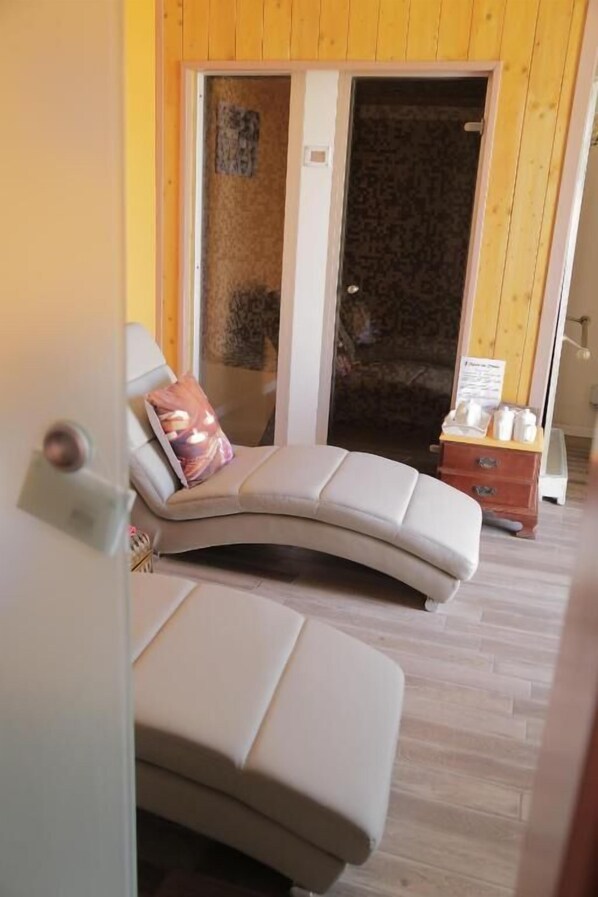 Una habitación con un sofá curvo, un armario de madera y una puerta que da a una estancia oscura.