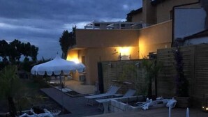 Une piscine dotée d’une terrasse en bois, de chaises longues et d’un espace salon abrité.