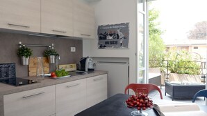 Una cocina moderna con estufa integrada, cafetera y comedor con mesa y sillas.