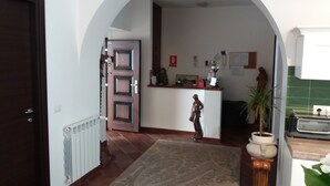 An arched doorway leading to a kitchen area with a tiled floor, a radiator, and a decorative rug. - BB Glicini (Rome)