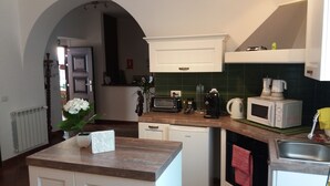 A compact kitchen with white cabinetry, a microwave, a coffee maker, and a small sink. - BB Glicini (Rome)