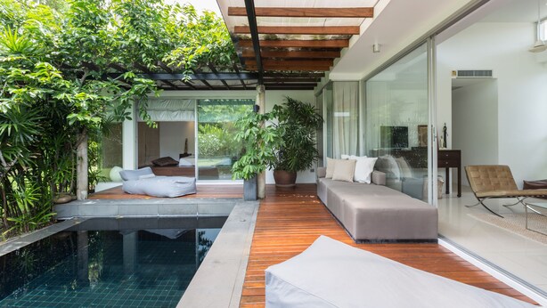 Un espacio exterior moderno con piscina, terraza de madera y asientos.