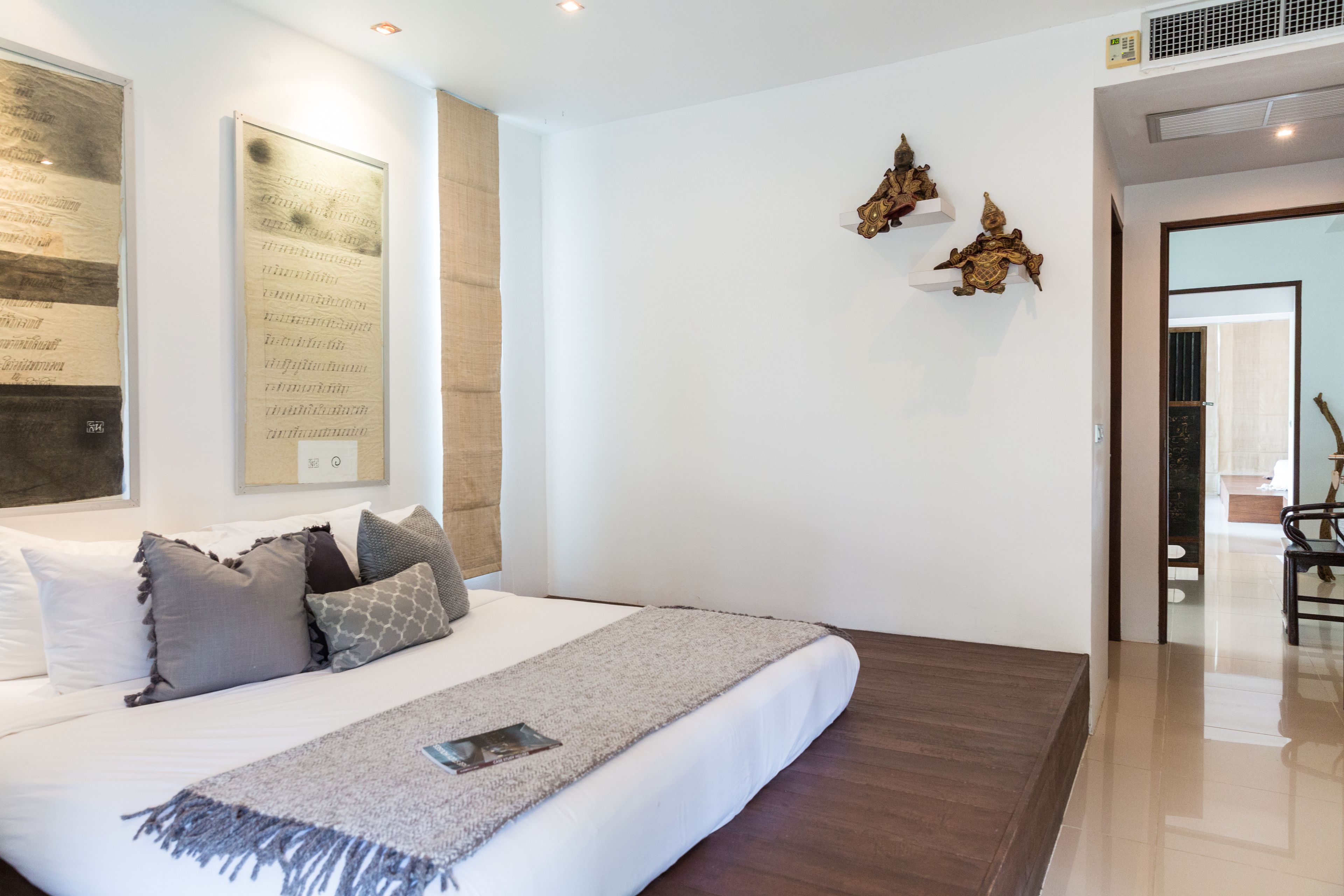 A modern bedroom with a large bed, a bedside table, and a wall-mounted artwork.