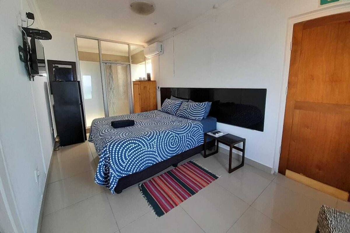 A bedroom with a bed, bedside table, and a door.