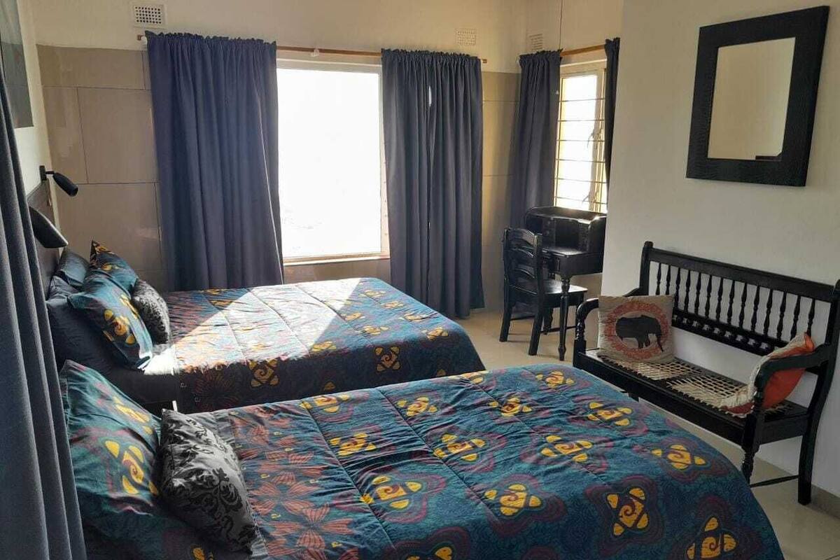 A room with two beds, a desk, a chair, and a bench.