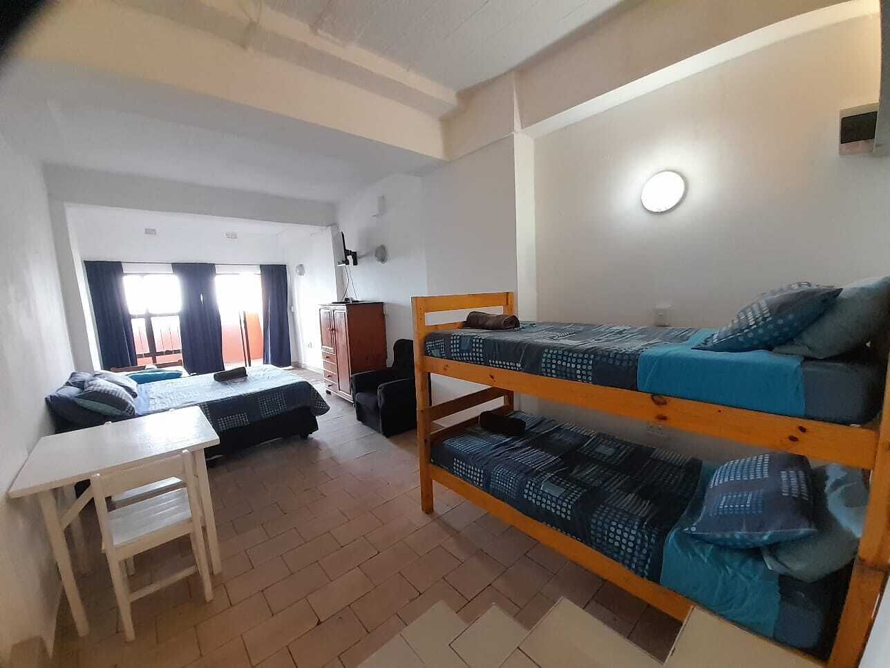 A dormitory room with bunk beds, a desk, and a chair.