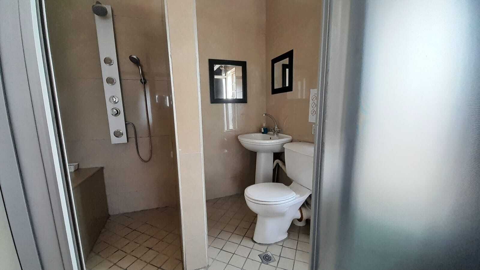 A small bathroom with a toilet, sink, and shower.
