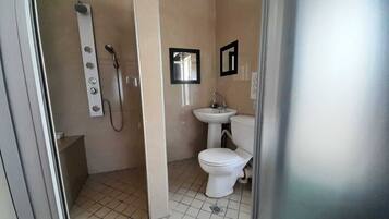 A small bathroom with a toilet, sink, and shower.