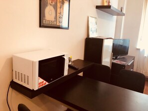 A kitchenette with a microwave, a small table, and a TV. - Logicasa Fuori le Mura (Como)