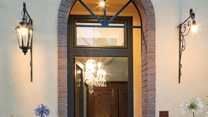 An entrance with a glass door, a chandelier, and a bed visible inside. - Corte Rosantico (Bussolengo)