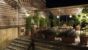 A covered outdoor area with a wooden pergola, potted plants, and a statue. - Corte Rosantico (Bussolengo)