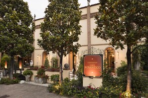 Une cour avec une pancarte indiquant : « MAISON D’HÔTES CORTE ROSANTICO ».