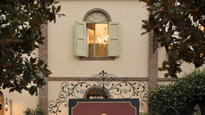 A sign for 'GUESTHOUSE CORTE ROSANTICO' with a decorative ironwork frame, surrounded by lush greenery and flowering plants. - Corte Rosantico (Bussolengo)
