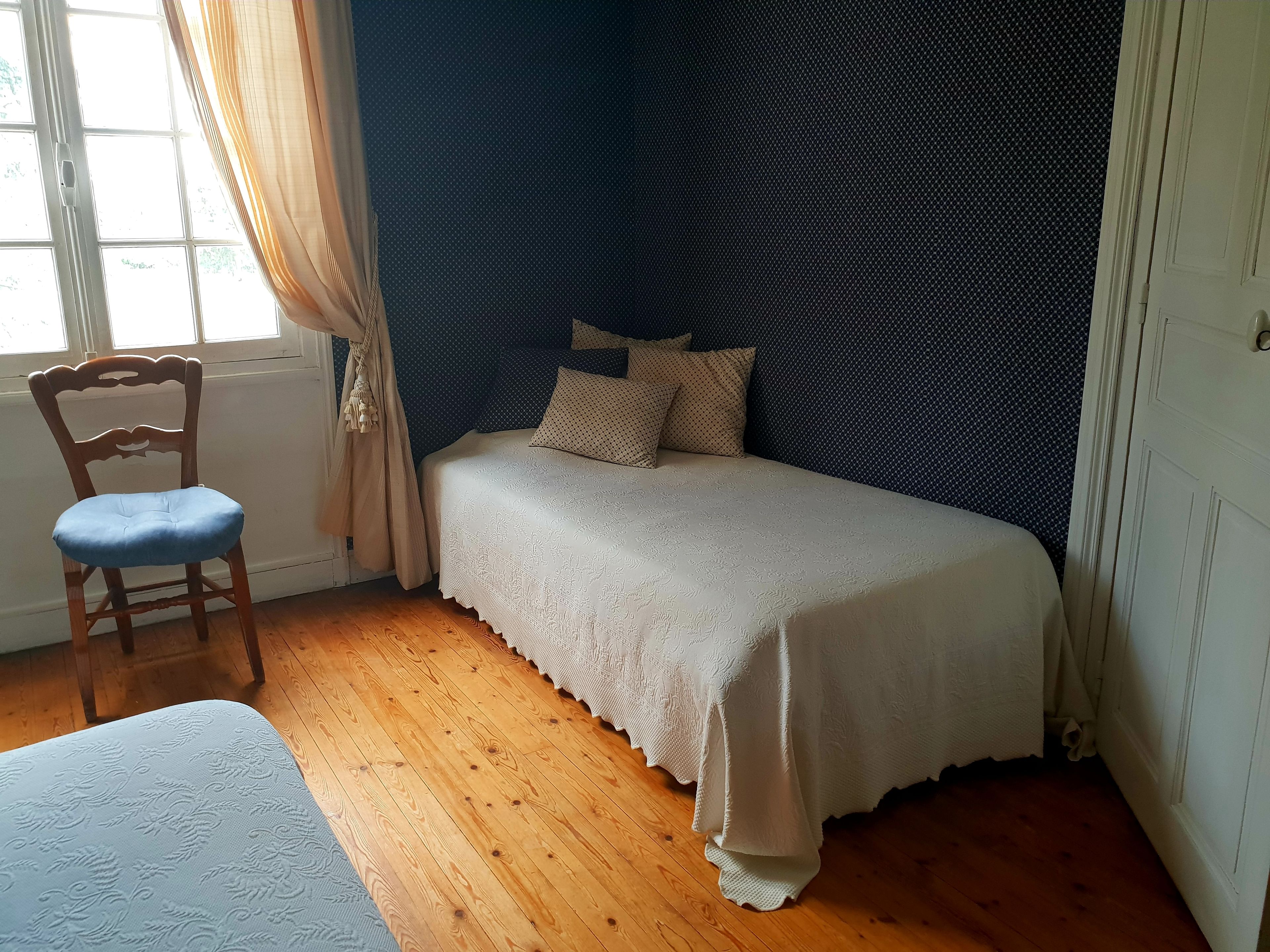 Una camera da letto con un letto, una sedia e una finestra.