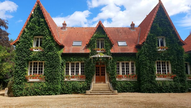 A traditional house with steeply pitched roofs, ivy-covered walls, and multiple windows with flower boxes. - Domaine de la Coudraye (La Haye-du-Theil)