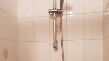 Une douche équipée d’un pommeau de douche à main et d’un robinet fixé au mur.