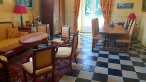A traditional dining room with a checkered floor, wooden furniture, and a dining table set for four. - Domaine de la Coudraye (La Haye-du-Theil)
