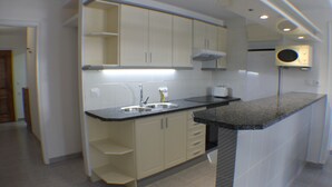 A modern kitchen with white cabinets, a granite countertop, and a built-in microwave.
