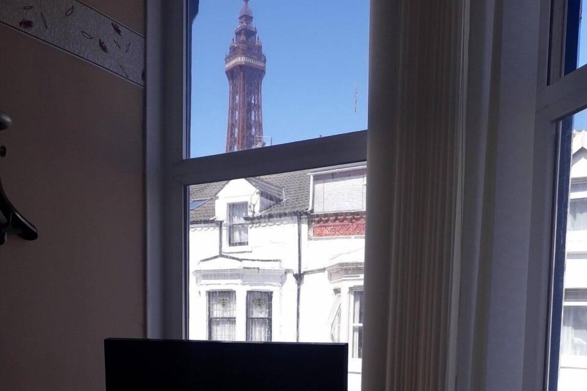 Quarto com uma janela grande que dá para um prédio com uma torre.